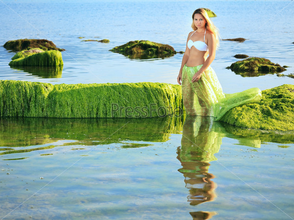 Beautiful woman like mermaid posing on the rock