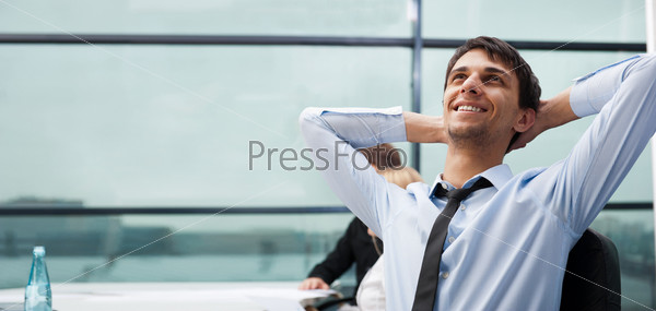 Расслабленный молодой мужчина в рубашке сидит в офисе
