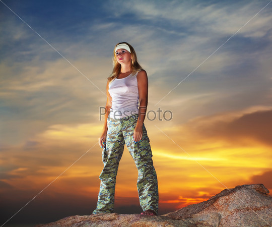 Military woman staying on the mountain peak at sunrise time