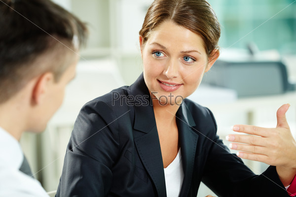 A woman manager looking at business partner during\
conversation