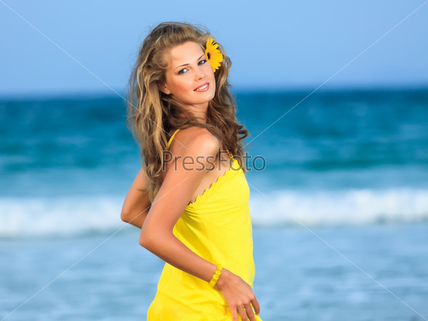 Beautiful woman in yellow dress on the beach