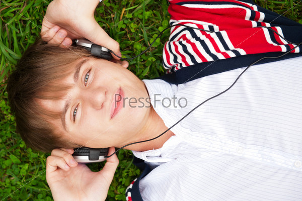 Student outside laying on grass and listening music school. Photo from above