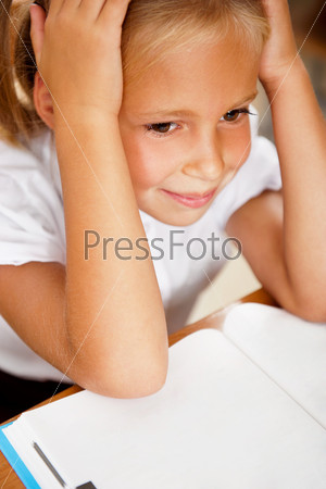 Image of smart child reading interesting book in classroom. Vertical Shot. She is tired