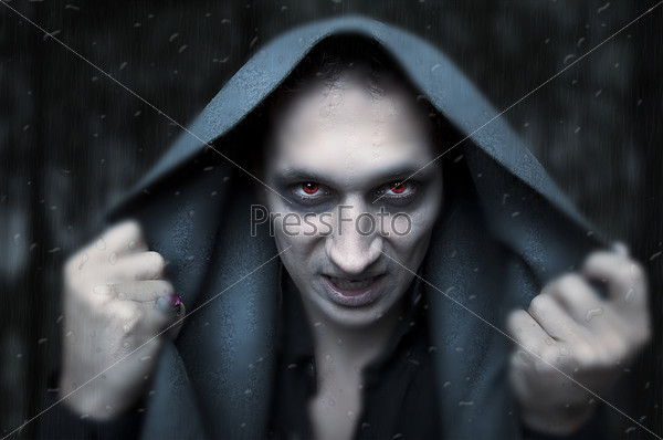 Portrait horrible fashion male vampire (demon or evil wizard)  knocking to rainy and misted window. Halloween concept