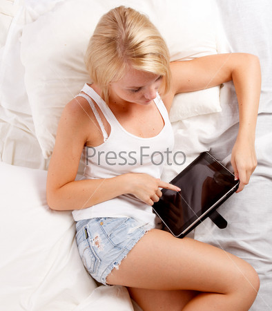 Young woman lying on the bed with tablet pc