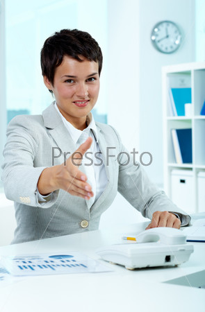 Portrait of pretty employer at workplace giving you hand for handshake