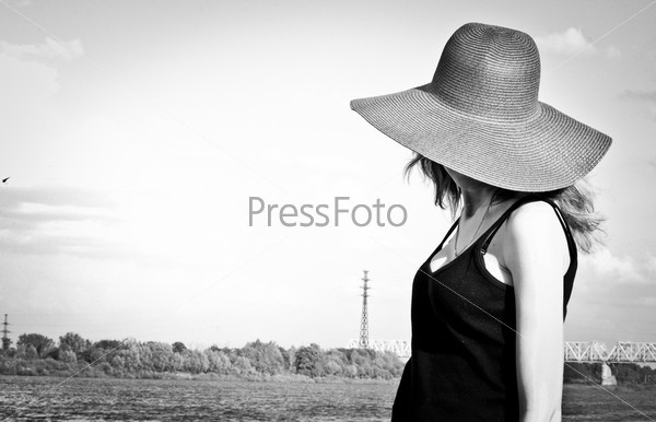 Черно-белая фотография. Девушка в шляпе на природе. Поля шляпы закрывают девушке лицо