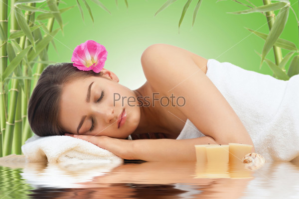 Portrait of young beautiful spa woman with flower in her hair lying and relaxing