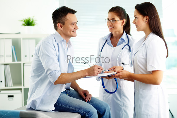 Portrait of confident female doctors and happy patient in hospital
