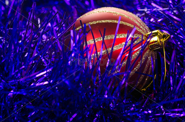 Красный рождественский шар в фиолетовой гирлянде