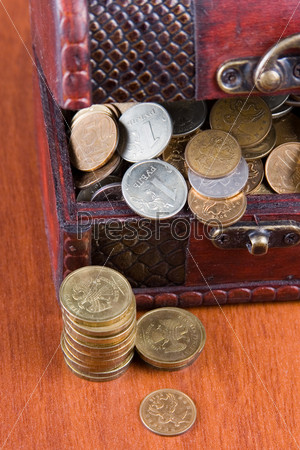 Open chest with coins on a wooden surface close-up