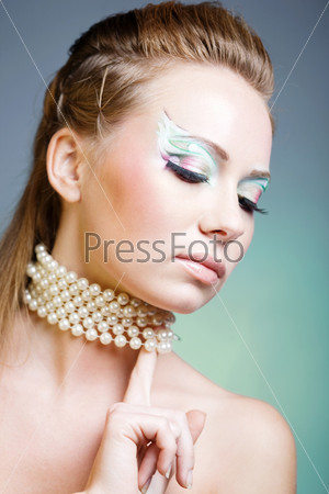 Fashion model with ceremonial make-up and face-art on blue studio background