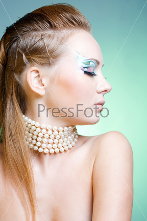Fashion model in profile with ceremonial make-up and face-art on blue studio background
