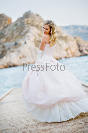 Beautiful bride wearing fluffy wedding dress posing at beach