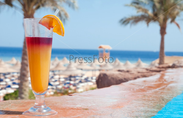 A glass of alcohol fruit cocktail at the pool near sea