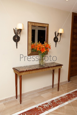 Интерьер фойе - стол с цветами, бра и зеркало