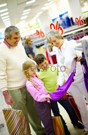 Portrait of happy grandparents and grandchildren choosing clothes in the mall