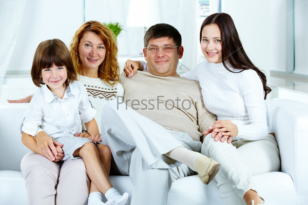 Photo of happy family looking at camera at home
