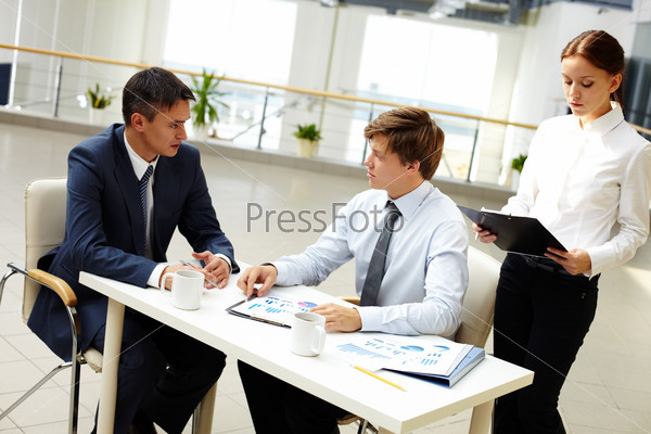 Office workers discussing financial statistics in office