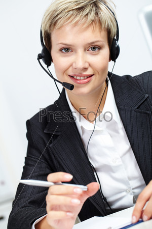 Portrait of young attractive secretary with headset looking at camera and smiling