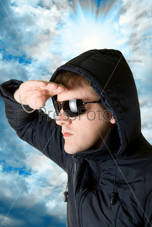 man staring into the distance in black sunglasses and jacket on blue sky background