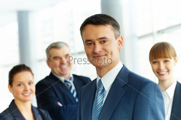 A young businessman smiling against three partners