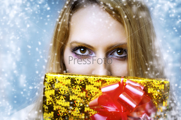 Bright makeup for eyes and christmas golden gift-box with red ribbon closeup
