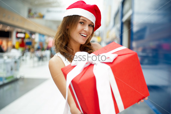 Excited attractive woman with big gift box standing at shopping
