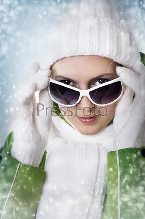 Молодая симпатичная девушка в зимней одежде и солнцезащитных очках
