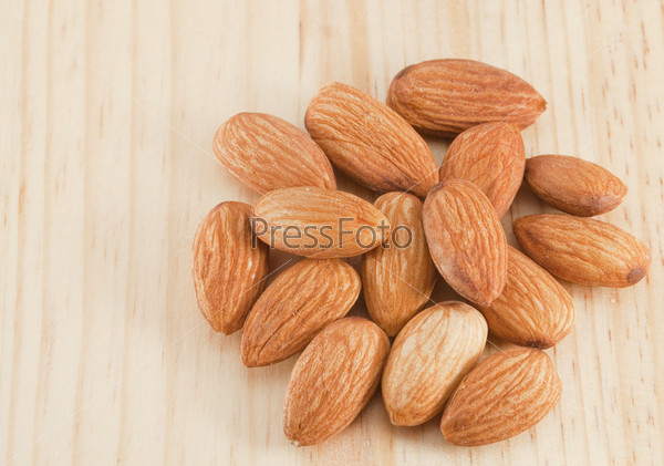 Pile of almonds on the wooden background. Space for your text