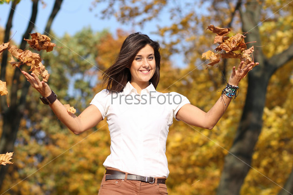 Portrait of a happy woman against yellow leaves, stock photo