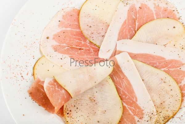 Sliced ham with sliced pear decorated isolated on a white, stock photo