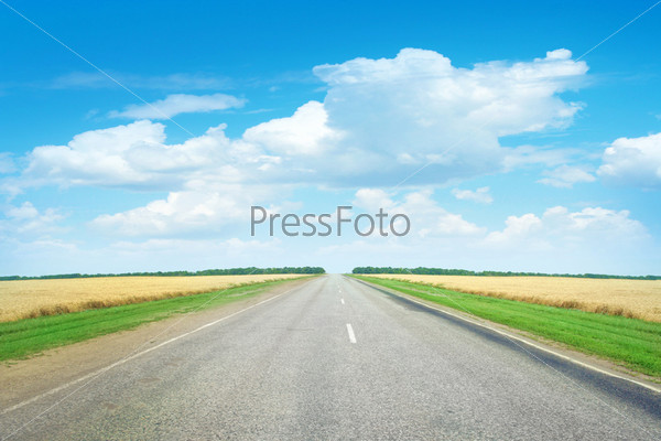 Пустая дорога через поле и голубое небо с облаками