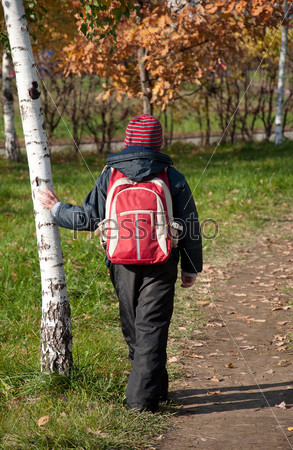 A boy with a backpack in the autumn City Park