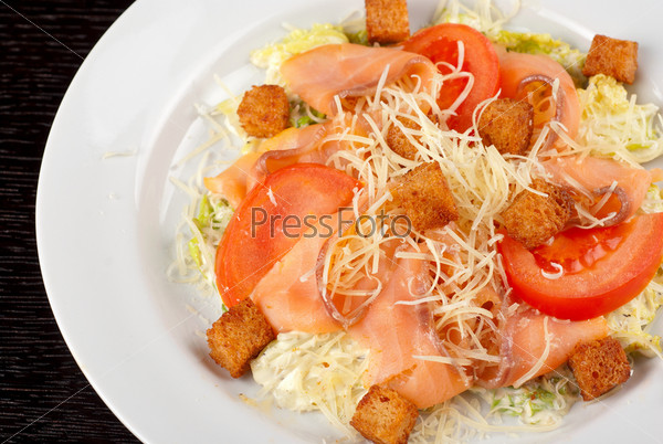 Salad of lettuce, chinese cabbage, tomato, garlic rusk, parmesan cheese, sauce and smoked salmon filet, stock photo