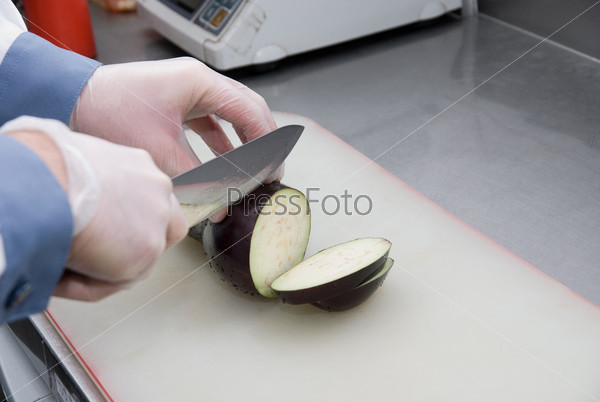 Cook cutting a zucchini at kitchen board, stock photo