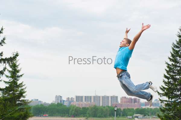 Happy young man jumping in air with arms extended