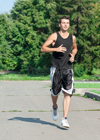 Young muscular man jogging in park