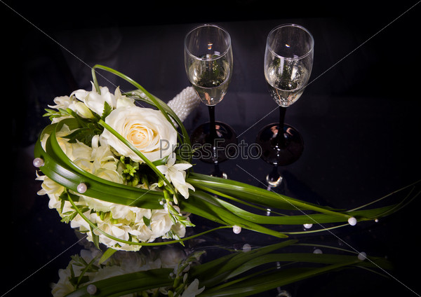 Two wine glasses of champagne and wedding bouquet on a black background