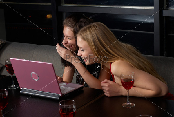 Group of young people with laptop and wine in cafe