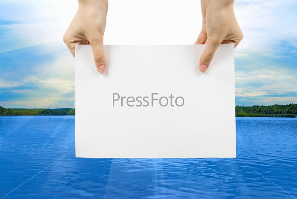 Hand with white paper on a summer lake background