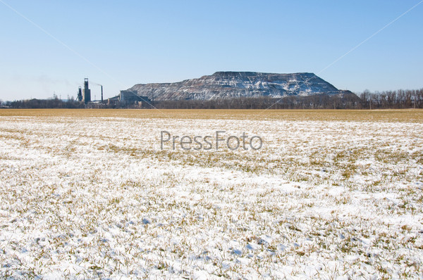 Artificial man-made rock near coal mine in Ukraine with winter field on foreground