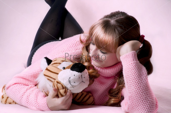 Beauty portrait of cute sexy brunette woman with soft toy. Female model lying on floor in the pink room. Little girl style