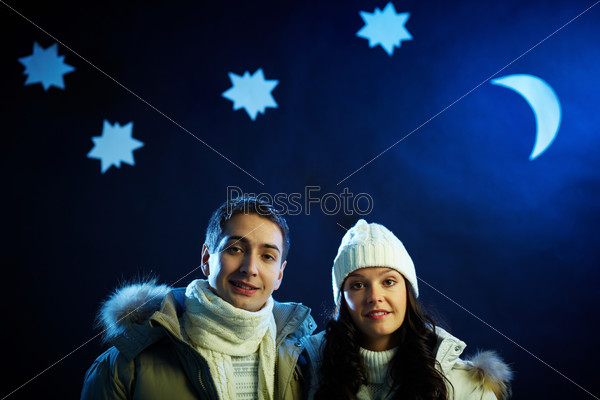 Portrait of happy couple looking at camera with moon and stars above their heads