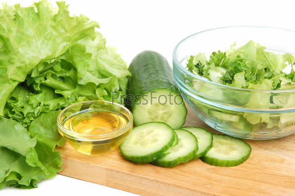Fresh tasty lettuce, vegetable oil and cucumber on a cutting board on white background