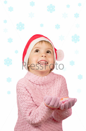 Cheerful child. The little girl happy in Santa hat catches\
snowflakes.