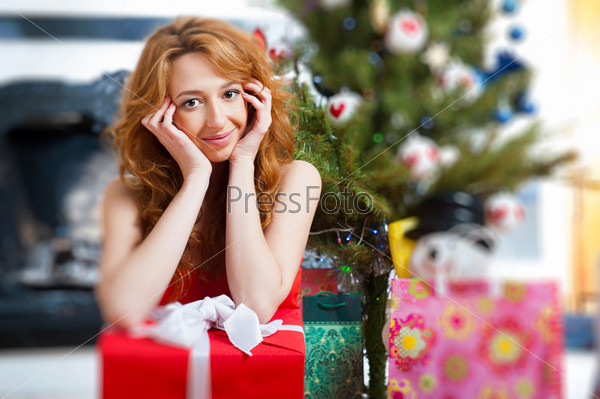 Christmas woman near a Christmas tree holding big gift box while sitting near Christmas Tree