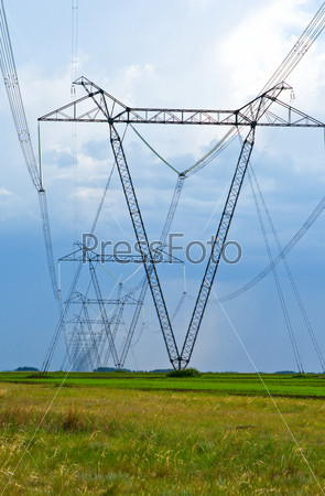 Electricity pylon and cables stretching out into the distance across a green field