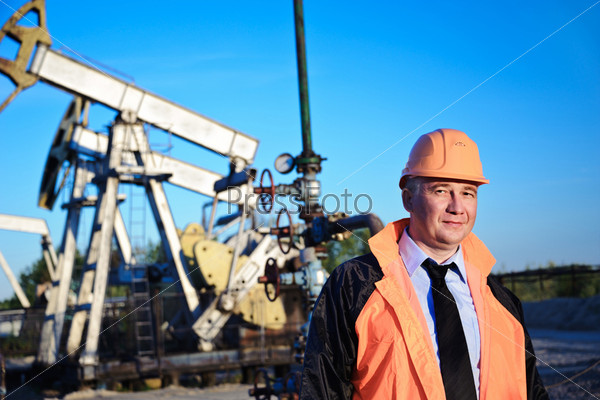 Работник нефтедобывающей промышленности на фоне качалок и голубого неба