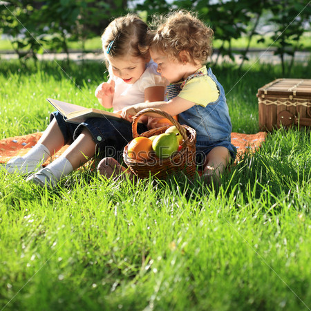 Дети читают книгу в парке